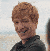 a man with red hair is smiling and wearing a black shirt