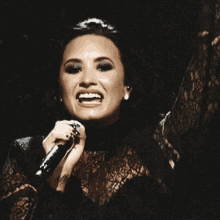 a woman singing into a microphone in a black lace top