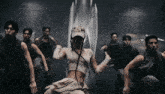 a group of people are dancing in a dark room and one of them is wearing a hat