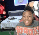 a man wearing a sweatshirt that says ' nba ' on it is sitting in a bedroom next to a bed .