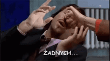 a man in a suit and tie is being attacked by a woman 's hands .