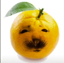 a yellow orange with a green leaf and a face carved into it