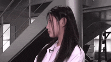 a woman with long hair is wearing a white shirt with a microphone around her neck