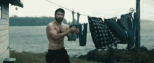 a shirtless man is standing next to a clothes line with clothes hanging from it .
