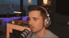 a man wearing headphones stands in front of a microphone with his mouth open