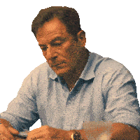 a man in a blue shirt is sitting at a table looking down