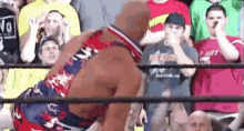 a man is wrestling another man in a wrestling ring while a crowd watches .