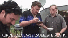 three men are standing next to each other and one of them is holding a bowl of food ..