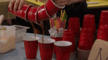 a person is pouring a drink into a red cup .