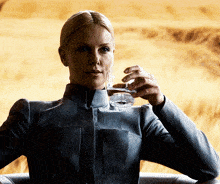 a woman in a gray jacket is drinking from a glass