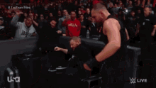 a wrestler is laying on the floor in a ring .