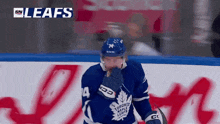 a hockey player wearing a toronto maple leafs jersey stands on the ice