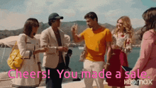 a group of people are standing next to each other with the words cheers ! you made a sale .