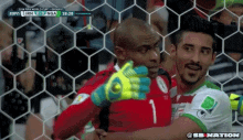 two soccer players are hugging each other in front of a goal during a world cup game