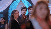 a man and a woman are standing next to each other in a crowd of people at a party .