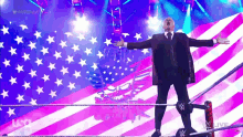 a man in a suit and tie stands in front of an american flag