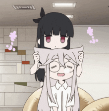 a girl with black hair is holding a pillow over a girl with white hair