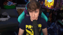 a man wearing headphones and a pikachu t-shirt talks into a microphone
