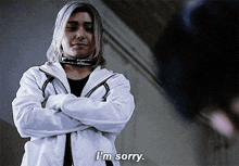 a man in a white jacket says i 'm sorry while standing with his arms crossed