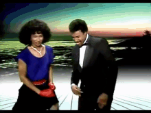 a man in a tuxedo and a woman in a blue shirt are dancing on a stage