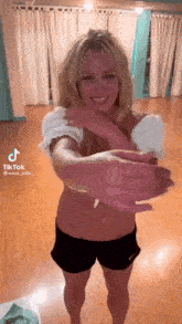 britney spears is standing in a room with her arms outstretched and smiling .