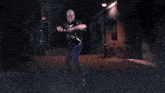a man holding a sword in a dark alleyway with a brick building in the background