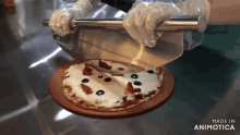 a person is cutting a pizza with a knife and it says made in animatica