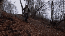 a man is running down a path in the woods covered in leaves