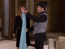 a man and a woman are standing next to each other and the man is holding a blue cloth