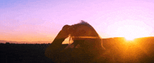 a woman looks through binoculars at the sun