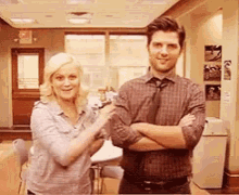 a man and a woman standing next to each other with their arms crossed .