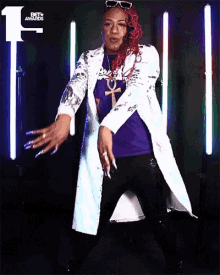 a woman wearing a white coat and a purple shirt is dancing in front of a bet awards logo