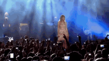 a woman is singing into a microphone in front of a crowd of people