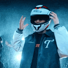 a man wearing a jacket with the letter t on it is putting on a motorcycle helmet