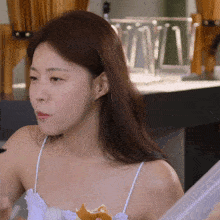 a woman in a white tank top is eating a hamburger
