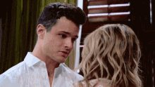 a man in a white shirt is looking at a woman with blonde hair