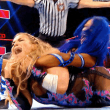 a female wrestler is laying on the ground while a referee stands behind her