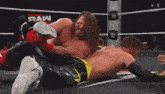 two wrestlers in a wrestling ring with the word raw on the wall