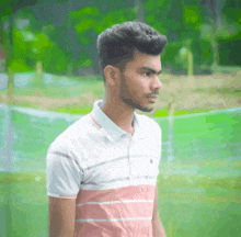 a young man with a beard wearing a pink and white shirt