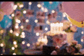 a birthday party with balloons , flowers , a cake , and lights .