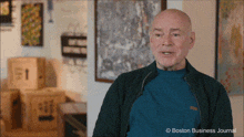 a bald man in a green jacket is talking in front of a boston business journal photo