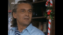 a man in a blue shirt is standing in front of a candy cane with a christmas wreath on it