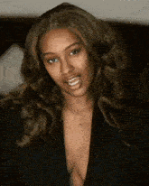 a woman wearing a black jacket and a plunging neckline smiles for the camera .