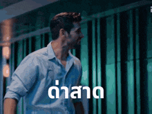 a man in a blue shirt is standing in front of a green wall with the word duard written in white letters