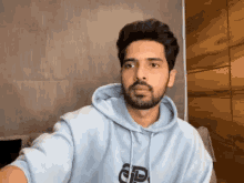 a man with a beard wearing a light blue hoodie with the letter p on it