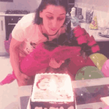 a woman blows out a birthday candle on a cake
