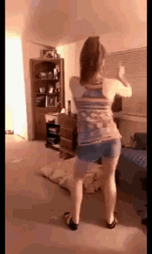 a woman is dancing in a living room while wearing shorts