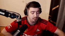 a man wearing headphones is sitting in front of a microphone in a room .