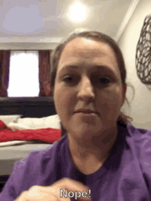 a woman in a purple shirt says nope on her face