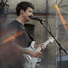 a man singing into a microphone while holding a guitar